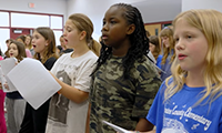  Students singing while holding sheet music.